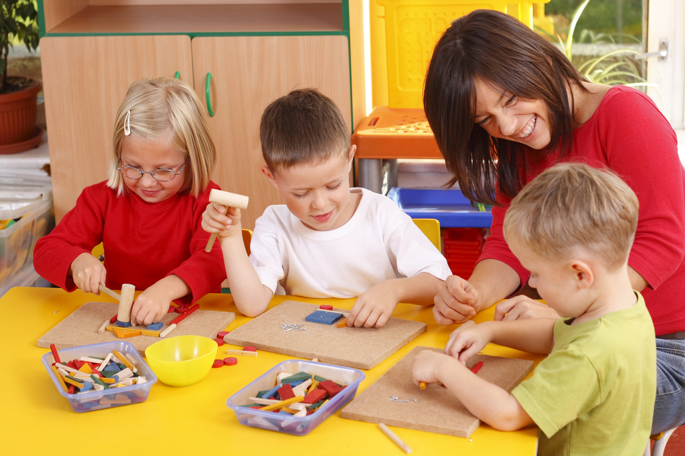 Teacher and preschoolers playing with wooden blocks