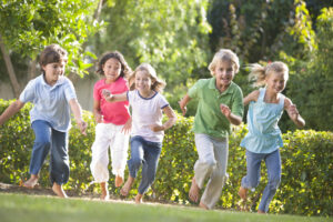 group of children running outdoors barefoot on grass
