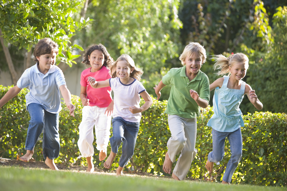 group of children running outdoors barefoot on grass