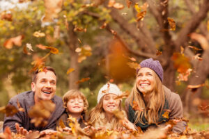 family smiling and playing in fall leaves outdoors
