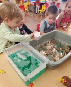 toddlers pouring water into sensory bins at preschool