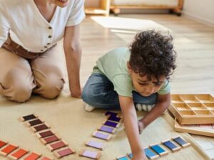 teacher helping preschool child with color sorting tiles