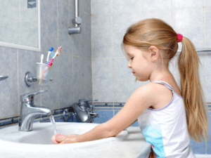young girl washing hands at bathroom sink