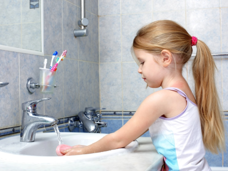 young girl washing hands at bathroom sink