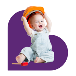 baby lifting toy construction hat while smiling