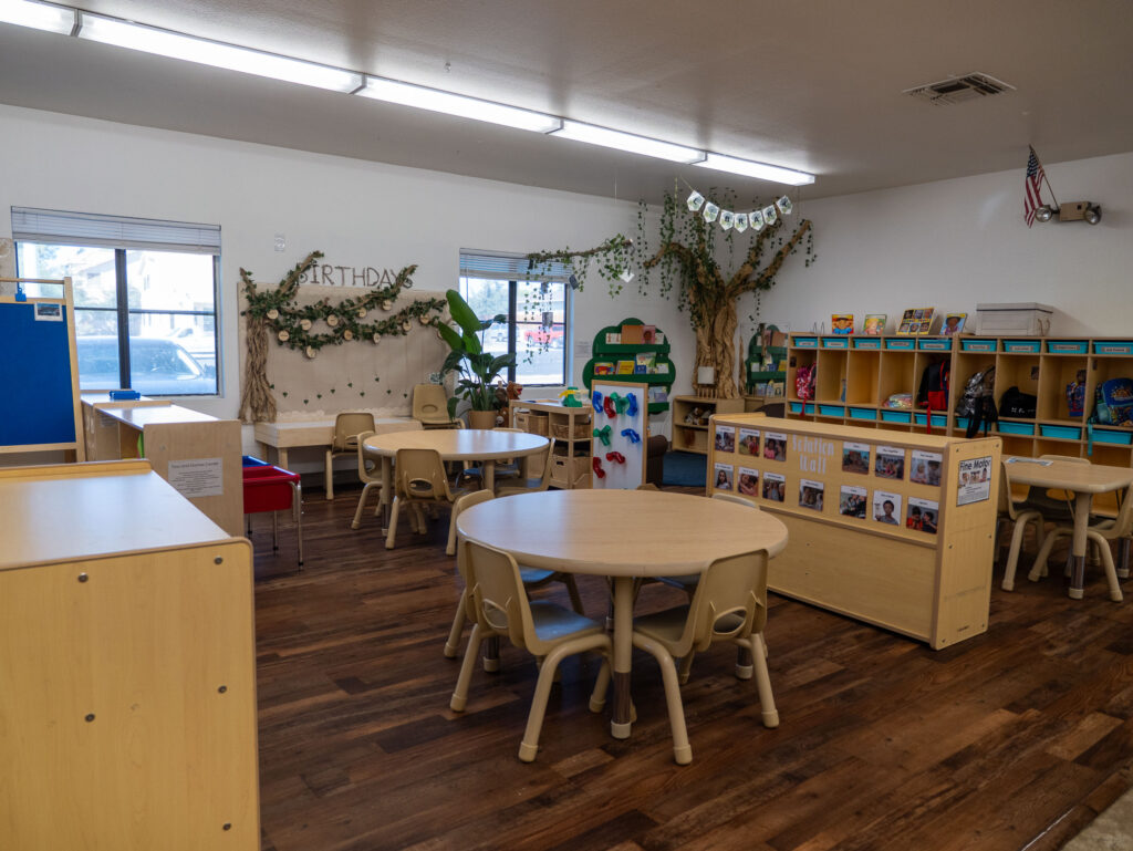 preschool classroom with round tables, learning centers, and nature decor