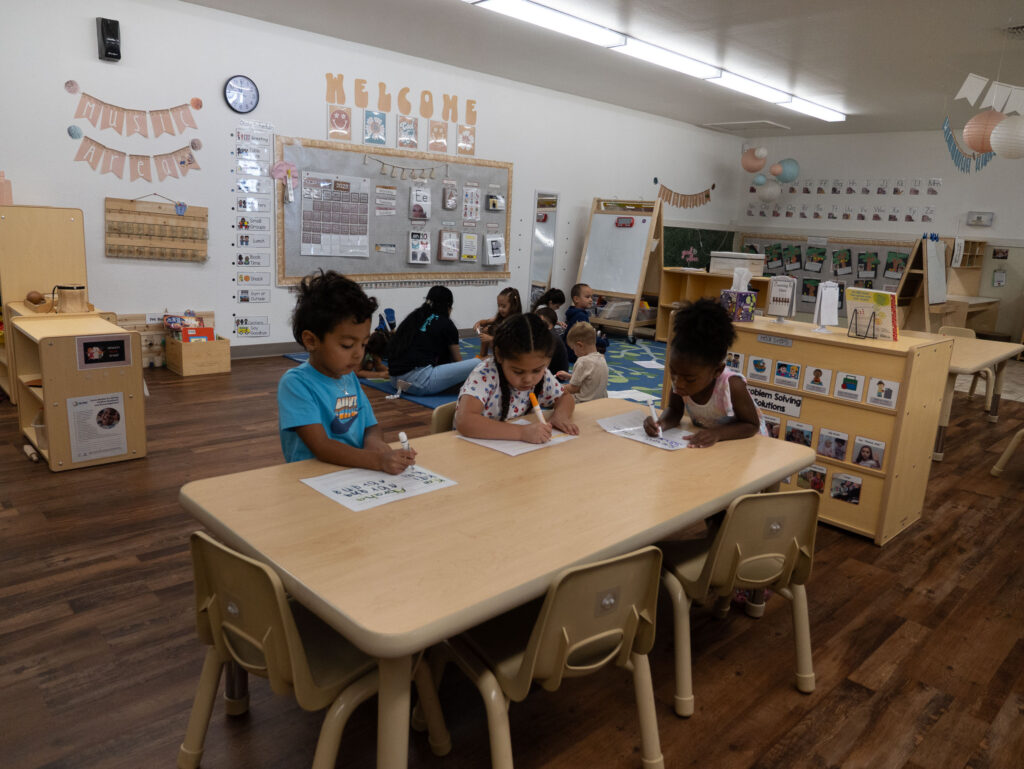kinder prep students writing at classroom table