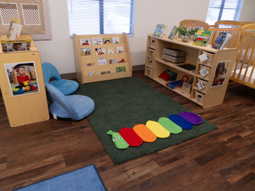 infant classroom play and nap area with activity gym and cribs nearby